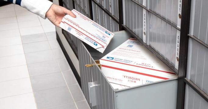 Person retrieving Priority Mail packages from an Extra Large PO Box.